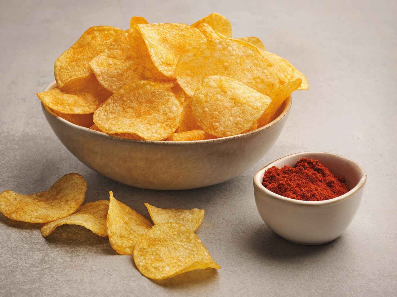 Hungarian-style chips with paprika in a bowl, next to it a small bowl with paprika powder.